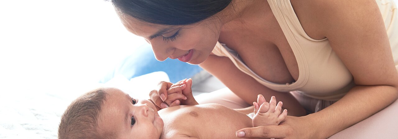 Una madre juega con su bebé en la cama.