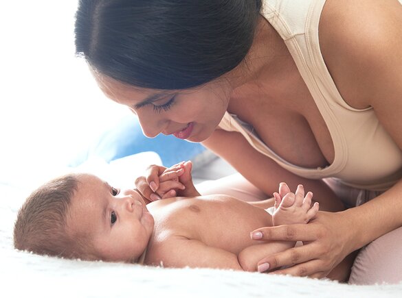 Een moeder speelt met haar baby op het bed.