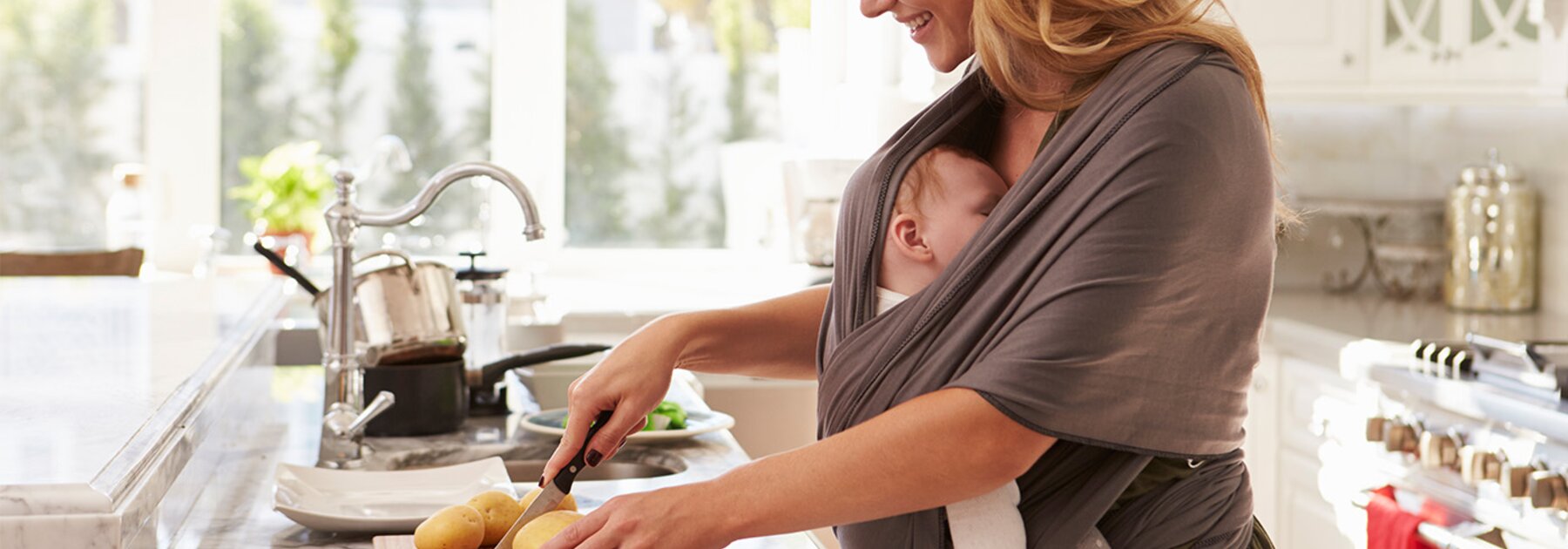 Een moeder bereidt een gezonde maaltijd om goede voeding tijdens de borstvoeding te ondersteunen, terwijl haar baby in een draagdoek slaapt die aan haar vastzit.