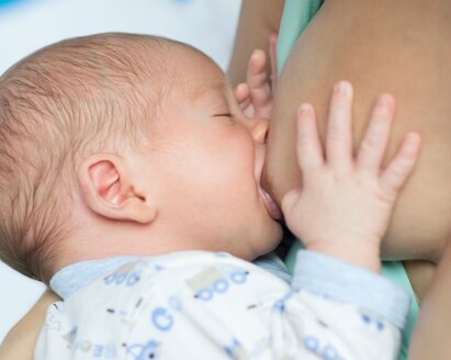 Baby drinking breast milk directly from mother's breast during breastfeeding session