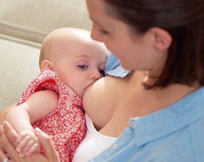 A mother is at home breastfeeding her baby.