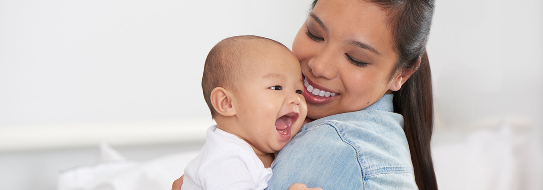 Een moeder houdt haar gelukkige baby vast en lacht.