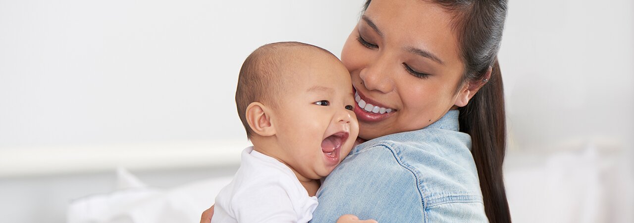 Una mamma tiene in braccio il suo bambino felice e sorride.