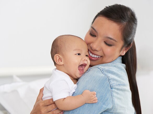 Een moeder houdt haar gelukkige baby vast en lacht.