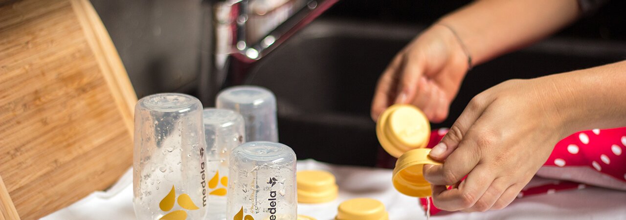 A mother washes Medela breast milk bottles and lays them on a towel to dry.