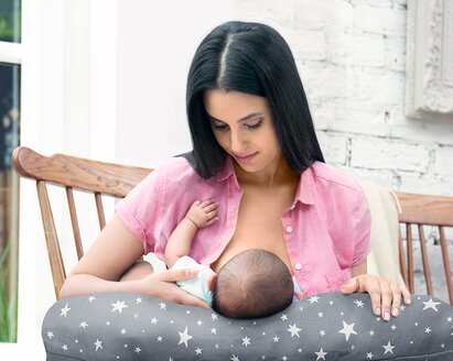 Una madre che allatta il suo bambino all'aperto su una sedia a dondolo.