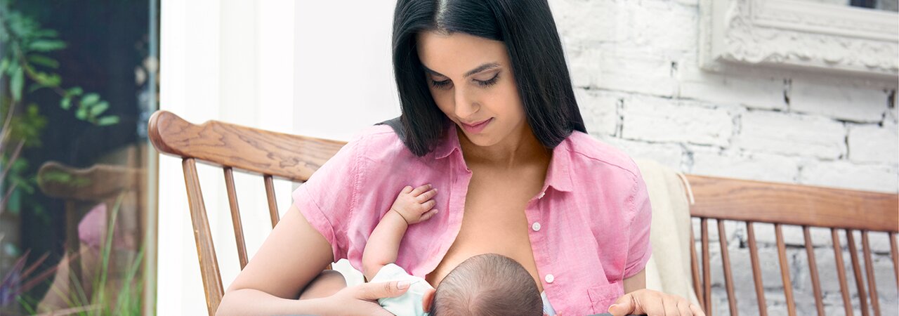 Una madre che allatta il suo bambino all'aperto su una sedia a dondolo.