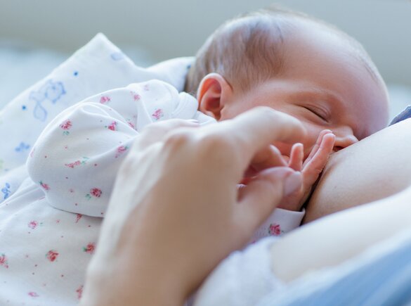 Um grande plano de uma mãe a amamentar a sua filha.