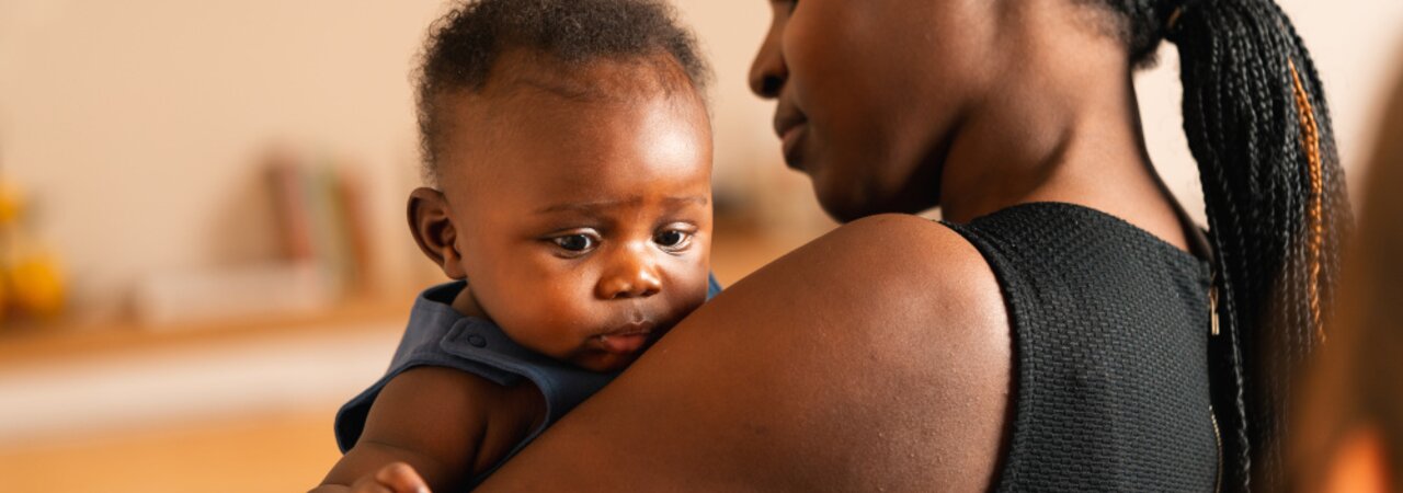 A mom holds her baby in her arms at home.