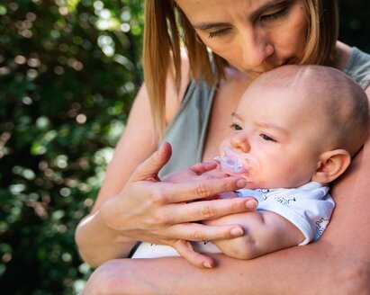 Eine Mutter tröstet ihr Baby, während sie draußen sitzen.