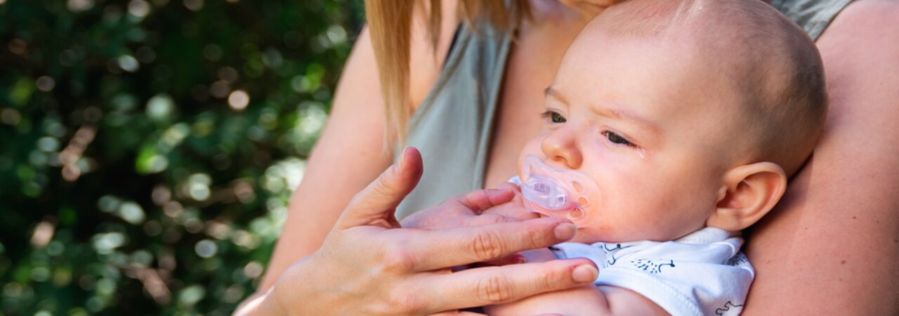 Eine Mutter tröstet ihr Baby, während sie draußen sitzen.