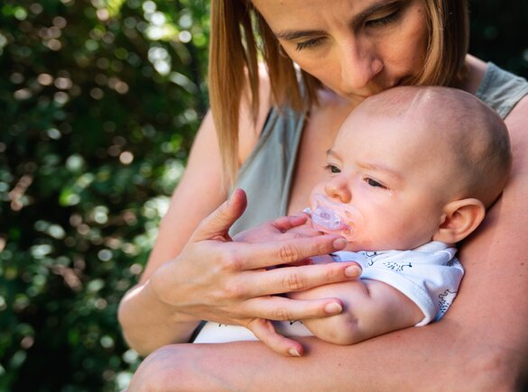 Eine Mutter tröstet ihr Baby, während sie draußen sitzen.