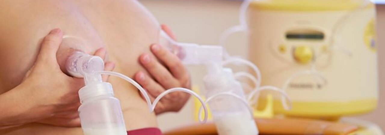 Woman sitting in a chair double pumping using a Medela Symphony breast pump.