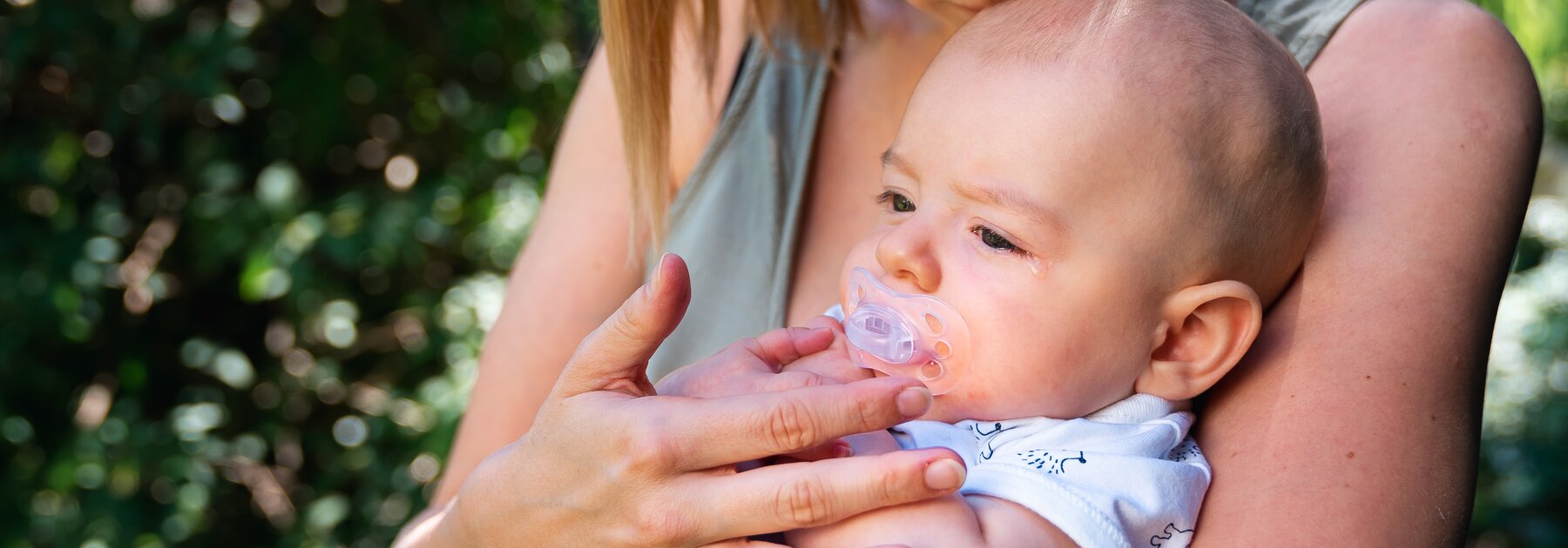Een moeder troost haar baby terwijl ze buiten zitten.