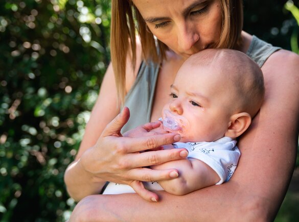 Een moeder troost haar baby terwijl ze buiten zitten.