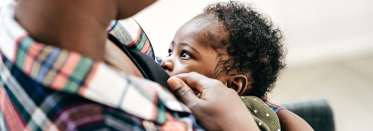 A mom breastfeeding her baby while it faces her.