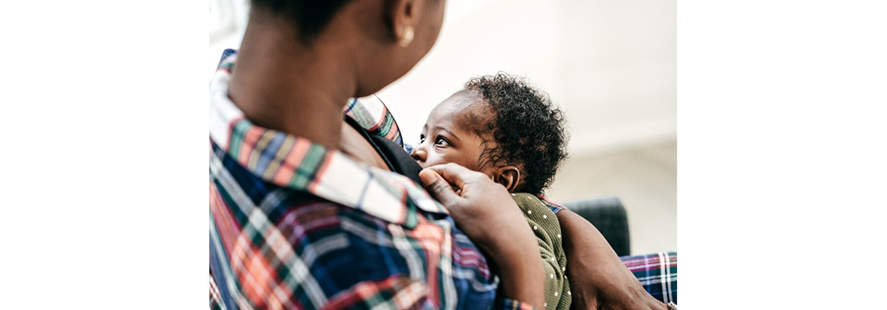 Een moeder die haar baby borstvoeding geeft terwijl hij naar haar kijkt.